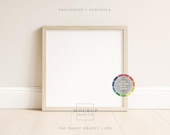May include: A square, light-coloured wooden picture frame with a white interior, leaning against a wall. The frame is on a light-coloured wooden floor. The image includes the text "Photoshop. Photopea" and a colour wheel with the text "One Mockup Many Looks!"