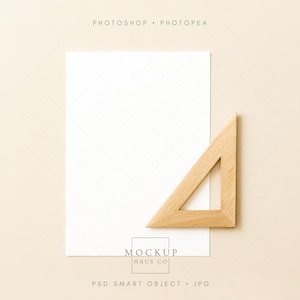 May include: A flat lay image featuring a white paper sheet and a wooden right triangle ruler on a beige background. The text "PHOTOSHOP • PHOTOPEA" is at the top, and "MOCKUP HAUS CO" is at the bottom, with "PSD SMART OBJECT • JPG" below it.