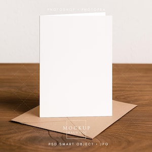Modello di biglietto piegato, biglietto d'auguri verticale bianco vuoto appoggiato su una scrivania in legno su una busta Kraft, modello PSD semplice, JPG incluso