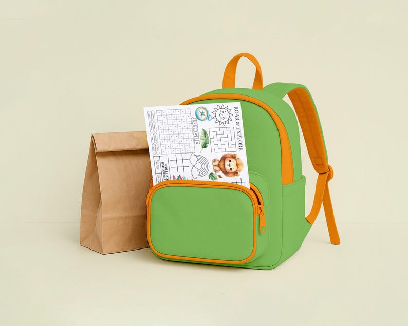 May include: A green backpack with orange accents and straps, a front pocket, and a zipper. A paper with a lion illustration and the text "ROAR & EXPLORE" is in the front pocket. A brown paper lunch bag is next to the backpack.