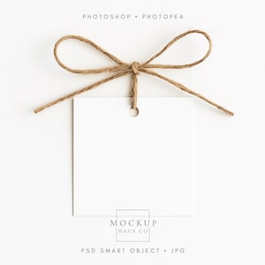 May include: A square white tag with a hole at the top is tied with a brown twine bow. The text "PHOTOSHOP • PHOTOPAE" is at the top. The text "MOCKUP HAUS CO" is at the bottom. The text "PSD SMART OBJECT • JPG" is at the bottom.