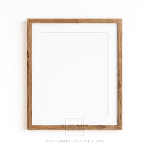 Op de afbeelding: Een vierkante houten fotolijst met een witte passe-partout. De lijst is gemaakt van lichtbruin hout en heeft een eenvoudig, klassiek ontwerp. De tekst "MOCKUP HAUS CO" staat in het midden onderaan de lijst.