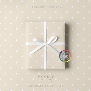 Peut inclure: Un coffret cadeau emballé avec un ruban et un nœud blancs, présenté sur un fond beige à pois. La boîte est enveloppée dans du papier beige à pois blancs. Le texte "Photoshop + Photopea" et "Mockup Haus Co." est inclus.