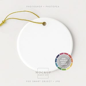 May include: A white, circular ceramic ornament with a gold string. The ornament has a small hole for the string. The image also includes a colour wheel and the text "Photoshop Photopea".