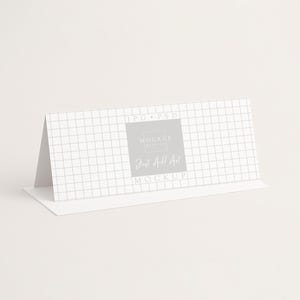 Pu&ograve; includere: Un biglietto bianco piegato con un motivo a griglia e il testo "Just Add Art Mockup" in un rettangolo grigio. Il biglietto &egrave; angolato, mostrando il fronte e il lato, su uno sfondo bianco.
