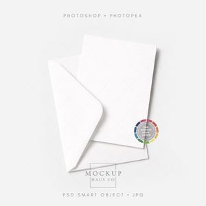 Puede incluir: Una maqueta de papeler&iacute;a blanca con una tarjeta en blanco dentro de un sobre abierto. La imagen incluye el texto "PHOTOSHOP &bull; PHOTOPAE" en la parte superior y "MOCKUP HAUS CO" y "PSD SMART OBJECT &bull; JPG" en la parte inferior. Tambi&eacute;n se ve un logotipo colorido.