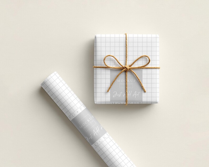 May include: A wrapped gift box and a roll of wrapping paper. Both are white with a grid pattern. The gift box is tied with twine and has a bow. The wrapping paper roll has a label that reads "Just All Art."
