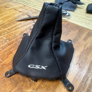 May include: Black leather gear shift boot with a silver embroidered "CSX" logo. The boot is attached to a metal frame with multiple mounting points.