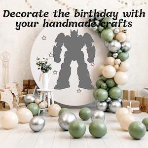 May include: A birthday party scene with a large white circle featuring a gray robot silhouette and star accents. Balloons in silver, green, and cream colors are arranged around the circle and on the floor. The text "Decorate the birthday with your handmade crafts" is at the top.