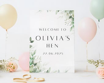 May include: White welcome sign with green foliage border. The text reads "Welcome to Olivia's Hen 22.06.2025".