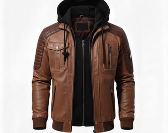 May include: A brown leather jacket featuring a black detachable hood with drawstrings, a front zipper closure, and a black inner layer. The jacket includes quilted shoulder panels, two chest pockets with flaps, two side pockets, and a sleeve pocket.