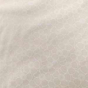 May include: A white fabric with a repeating pattern of white stylized flowers. The flowers have a dotted center.