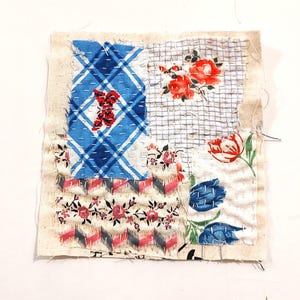 May include: A square textile patch featuring a patchwork design of various fabric scraps in blue, white, red, and green. The piece includes patterns of plaid, floral prints, and tulips, all joined together with visible white running stitch embroidery.