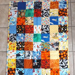 May include: A colorful patchwork quilt with a variety of patterns, including airplanes, animals, and geometric designs. The quilt is made up of 49 squares, each with a different pattern. The quilt is blue, green, yellow, orange, red, and black.