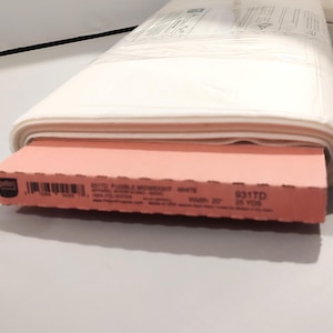 May include: A roll of white fabric with a pink cardboard insert. The fabric is wrapped in clear plastic. The cardboard insert has text that reads "931TD FUSIBLE LIGHTWEIGHT WHITE". The fabric is 20 inches wide and 25 yards long.