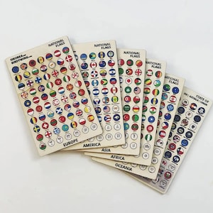 Op de afbeelding: Een verzameling houten rechthoekige platen met verschillende nationale vlaggen. Elke plaat is gelabeld met de tekst "NATIONAL FLAGS" en de naam van een continent. De vlaggen zijn in een cirkelvorm gerangschikt, met de tekst "SIKORKA. BIRDYWING.COM" op één plaat.