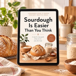 Pode incluir: Um tablet digital exibindo a capa de um livro intitulada Sourdough Is Easier Than You Think, A Beginner's Guide to Making Confident, Beautiful Bread. A capa apresenta um pão, uma tigela de farinha, uma colher de madeira e um pote de fermento.