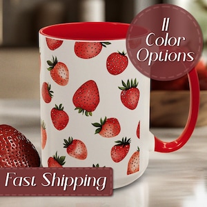 Puede incluir: Una taza de cerámica blanca con interior y asa rojos, adornada con un patrón de fresas rojas. La taza tiene el texto "11 Color Options" en un diseño circular.