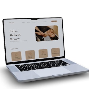 May include: A silver laptop displaying a website for Aura, a spa and wellness center. The website features the text "Relax. Refresh. Renew." and offers services like facial treatments, massage therapy, body care, and aromatherapy. A woman is shown receiving a massage.