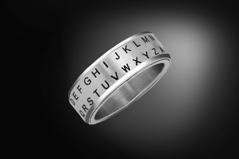 May include: A silver ring with a rotating band that has the alphabet engraved on it.