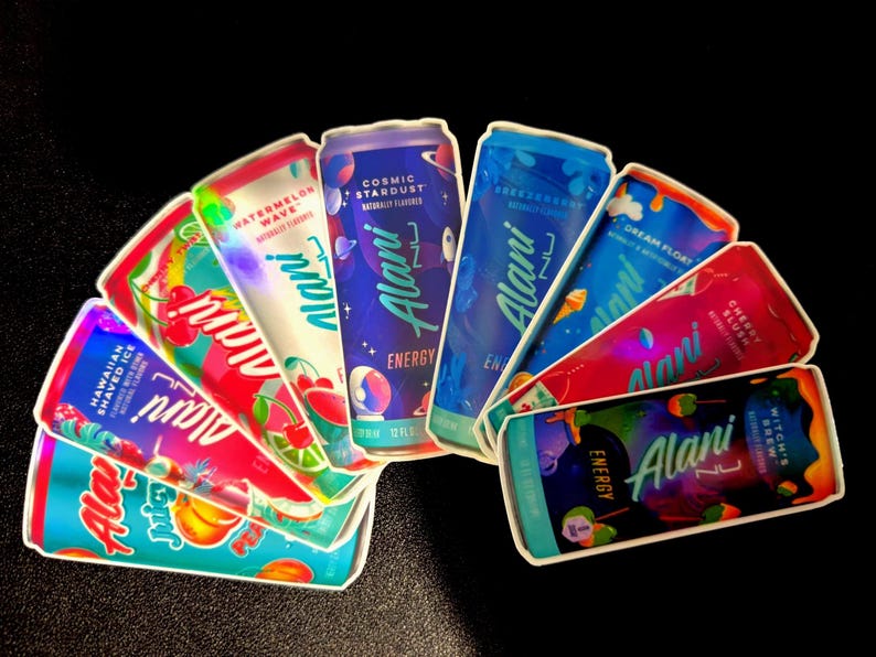 May include: An assortment of Alani Nu Energy drink cans, featuring various flavors like Hawaiian Shaved Ice, Watermelon Wave, and Cosmic Stardust. The cans are brightly colored with fruit and space-themed graphics, and the text "Alani Nu Energy" is prominently displayed.