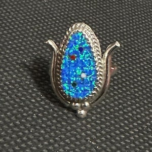 May include: A silver ring with a blue, green, and red mosaic design in the shape of a flower.