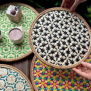 Puede incluir: Juegos de manteles individuales redondos tejidos con diversos patrones y bordes naturales. Un mantel individual presenta un diseño geométrico verde, otro un patrón en blanco y negro y un tercero un diseño colorido.