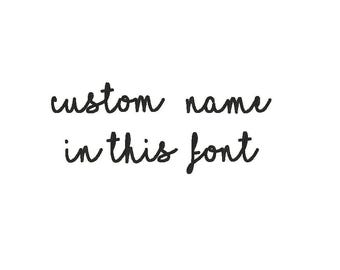 May include: A white background with black cursive text that reads "custom name in this font". The text is in a handwritten style, suggesting personalization or custom design options for various products.