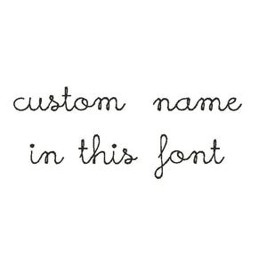 May include: White background with the text "custom name" and "in this font" written in a delicate, cursive script. The text is in black and is centered on the image.