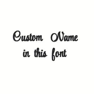 May include: White background with the text "Custom Name in this font" in a black, cursive script. The text is centered and the font is a flowing, elegant style, suitable for personalized items.