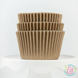 May include: A stack of brown cupcake liners. The liners are made of paper and have a fluted design.