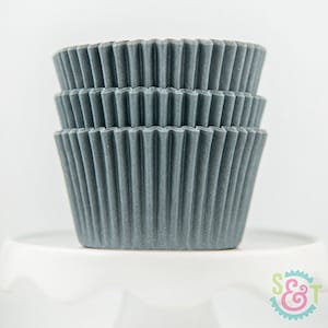 May include: A stack of gray cupcake liners. The liners are made of paper and have a fluted design.
