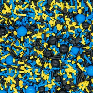 May include: A mix of blue, yellow, and black sprinkles. The sprinkles are in the shape of small balls, long cylinders, and small discs.