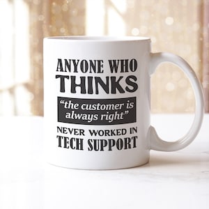 May include: A white ceramic mug with a curved handle. The mug features black text that reads: "ANYONE WHO THINKS 'the customer is always right' NEVER WORKED IN TECH SUPPORT."