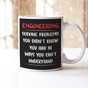 May include: White ceramic mug featuring the word "ENGINEERING" in red, with a humorous quote in white text on a black background. The mug has a curved handle and is suitable for hot or cold drinks.