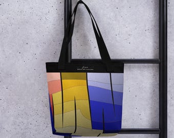 Peut inclure: Sac fourre-tout noir avec un motif abstrait coloré. Le motif présente des blocs de couleurs dans les tons rose, jaune, bleu et beige. Le sac a des anses noires et le texte "Bold Art Gallery".