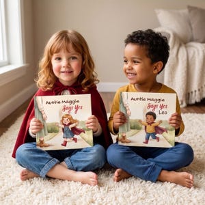 May include: Two children holding illustrated storybooks titled Auntie Maggie Says Yes. The books feature a drawing of a child in a cape running toward an adult. The children are wearing casual clothing, including a red cape and a mustard yellow shirt.