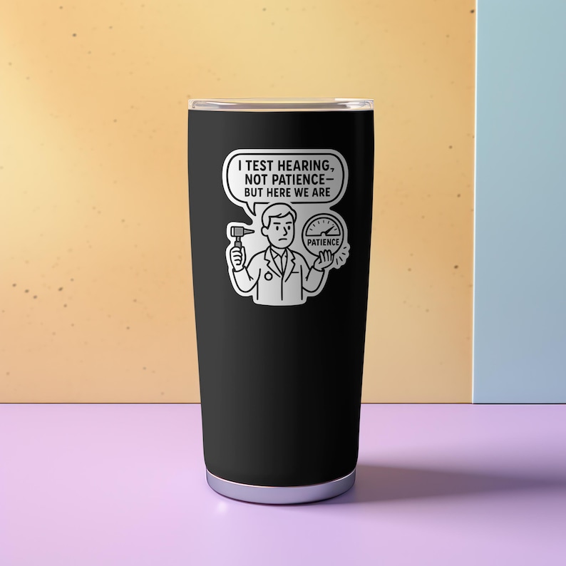 Puede incluir: Vaso t&eacute;rmico negro con borde plateado. El vaso tiene una pegatina blanca con un dibujo de un m&eacute;dico sosteniendo un diapas&oacute;n y un medidor de paciencia. El texto de la pegatina dice: "PRUEBO LA AUDICI&Oacute;N, NO LA PACIENCIA - PERO AQU&Iacute; ESTAMOS."