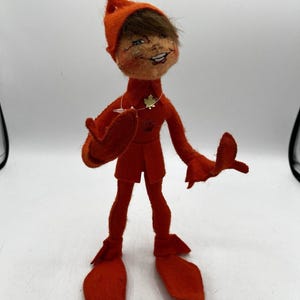 Puede incluir: Un letrero de madera rústico blanco con la palabra "Welcome" escrita a mano. Tiene un pequeño corazón decorativo adjunto. El fondo es una superficie de madera borrosa.