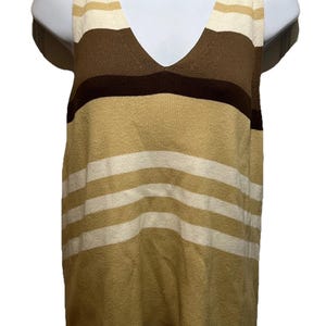 May include: A sleeveless V-neck top with horizontal stripes in shades of beige, brown, and cream. The top is displayed on a white mannequin, showcasing its design and color palette. The knitwear garment has a classic, versatile style.