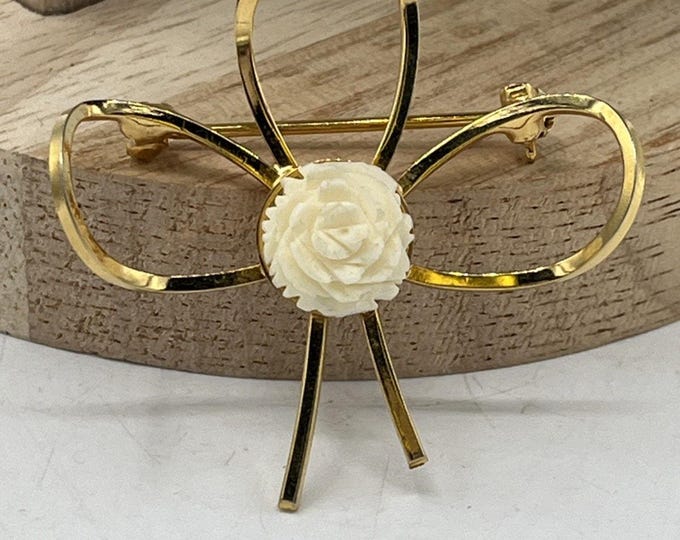 Vintage 1960’s gold tone brooch has four loops with a carved off white flower