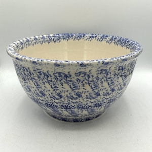 Może przedstawiać: Okrągła ceramiczna miska do mieszania z kremowym wnętrzem oraz niebieskim, gąbczastym lub nakrapianym wzorem na zewnątrz i na górnej krawędzi. Misa posiada szeroki otwór oraz gładki, zaokrąglony korpus z grubym, wykończonym brzegiem.