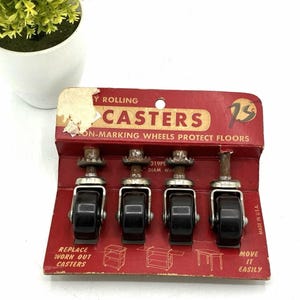 Può includere: Un set di quattro rotelle vintage montate su un cartoncino espositivo rosso. Ogni rotella presenta una ruota nera, una staffa in metallo argentato e uno stelo metallico dentellato. La confezione riporta le scritte Easy Rolling Casters, Non-Marking Wheels Protect Floors, Replace Worn Out Casters e Move It Easily.