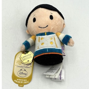 May include: A plush toy of Prince Eric with black hair, wearing a white and blue military-style jacket with gold buttons. The toy has a tag that reads Limited Edition and Wedding Prince Eric, along with a Hallmark Itty Bittys brand label.