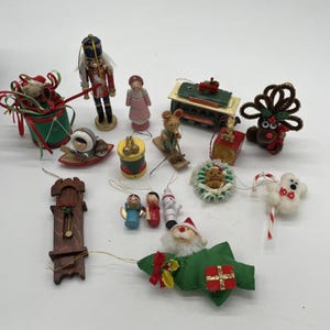 May include: A collection of Christmas ornaments, including a nutcracker, a Santa Claus figure, a wooden clock, and various other festive decorations. The ornaments are in various shapes and sizes, with a mix of colors and materials.