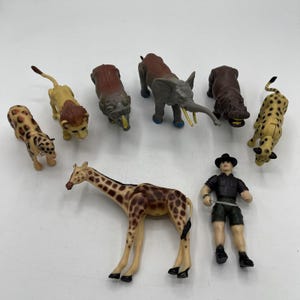 May include: A collection of plastic toy safari animals, including a giraffe, elephant, lion, and cheetah. A safari guide figure is also included. The toys are in various colors and sizes, perfect for imaginative play.