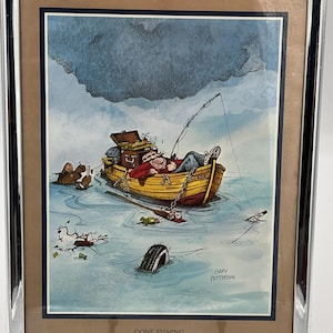 May include: Framed print titled "Gone Fishing" featuring a cartoon illustration of a man napping in a yellow boat. The boat is in a body of water with a fishing rod, a tire, and other details. The sky is gray and cloudy.