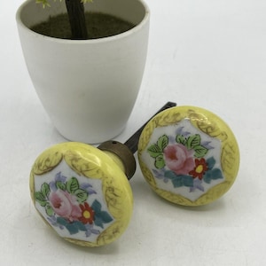 Juego de pomos de puerta de porcelana antigua con diseño floral amarillo y husillo de latón pintado a mano.