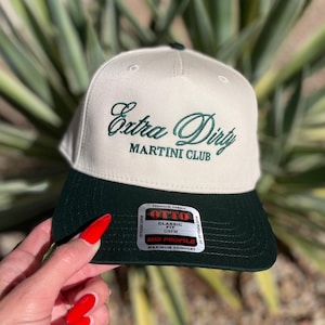Peut inclure: Casquette de baseball crème et vert foncé avec l'inscription "Extra Dirty MARTINI CLUB" en vert. La casquette est de coupe classique et fabriquée en tissu de qualité supérieure. Style mi-profil.