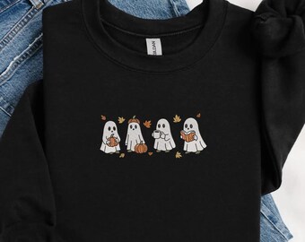 May include: Black sweatshirt with an embroidered design of four cartoon ghosts. Each ghost is shown with a different item: a pumpkin, a pumpkin, a coffee cup, and a book. Autumn leaves are scattered around the ghosts.